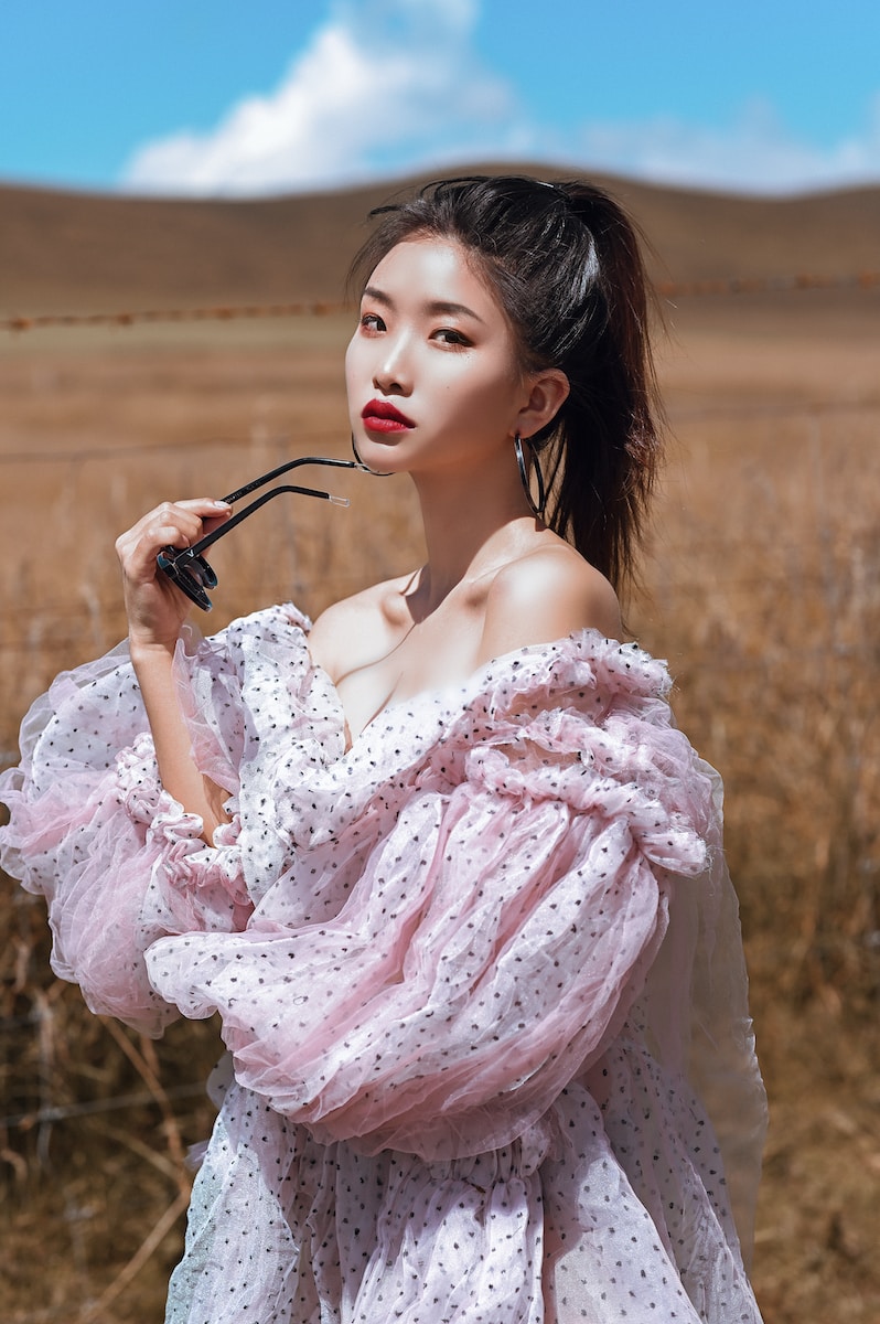 Woman In Pink Floral Dress Holding Black Sunglasses